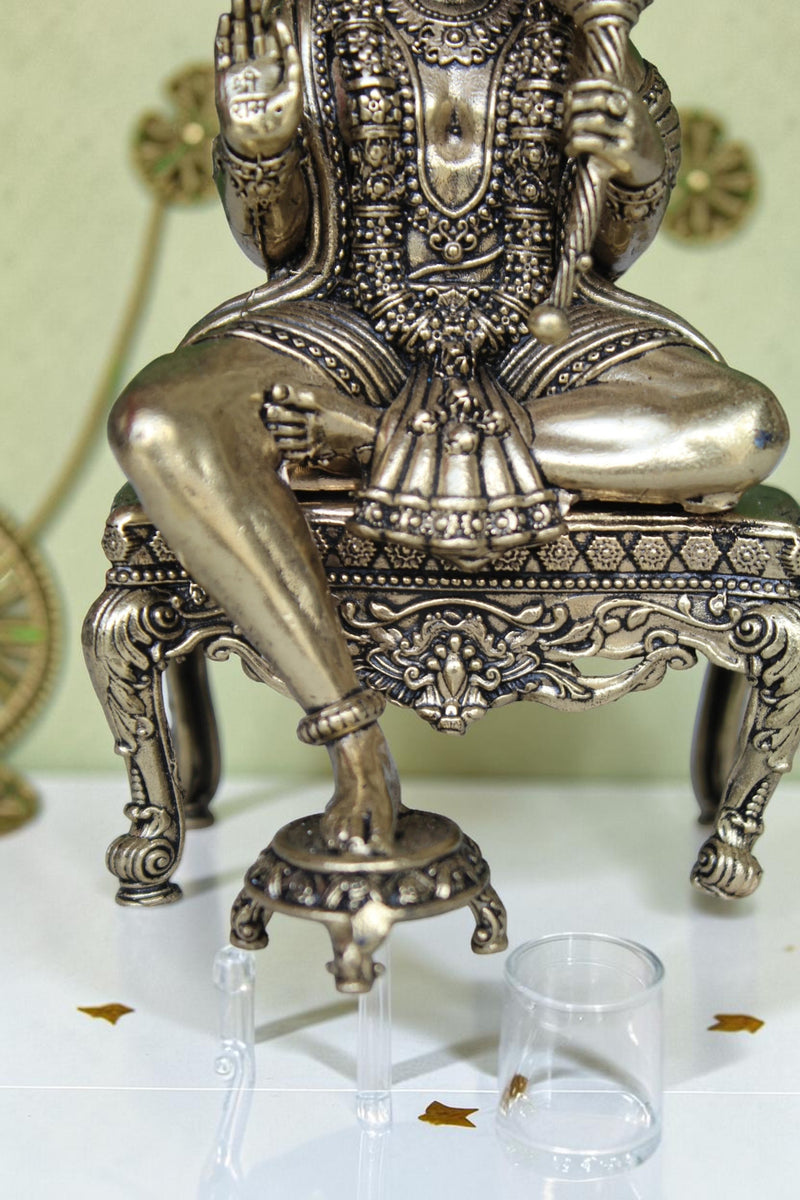 Rigvedaa™ brass Hanuman Ji idol sitting on an ornate throne, holding a mace, with intricate detailing and golden finish.