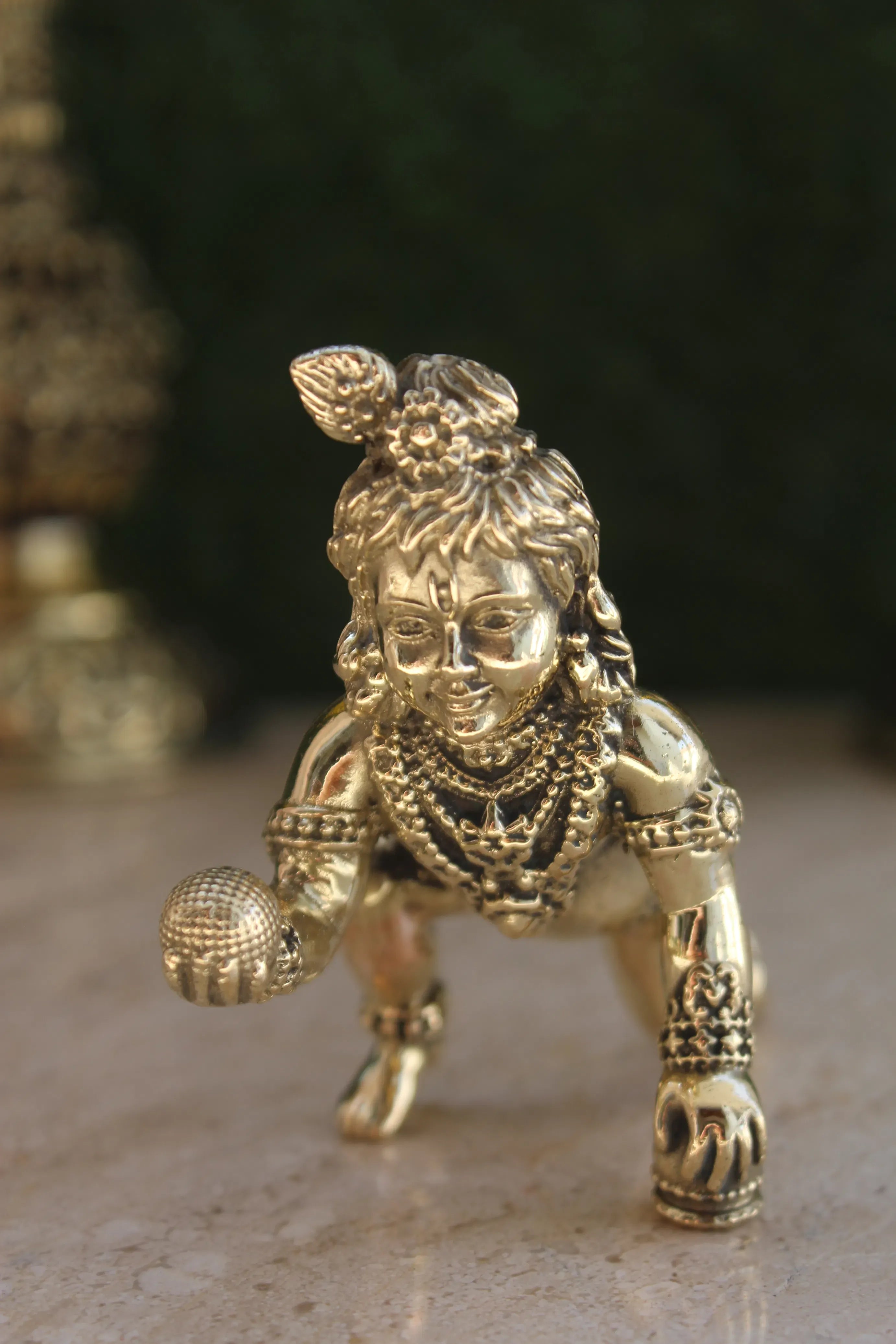 Brass Laddu Gopal Idol frontal view showing Baby Krishna holding sacred Laddu with ornamental jewelry and decorations