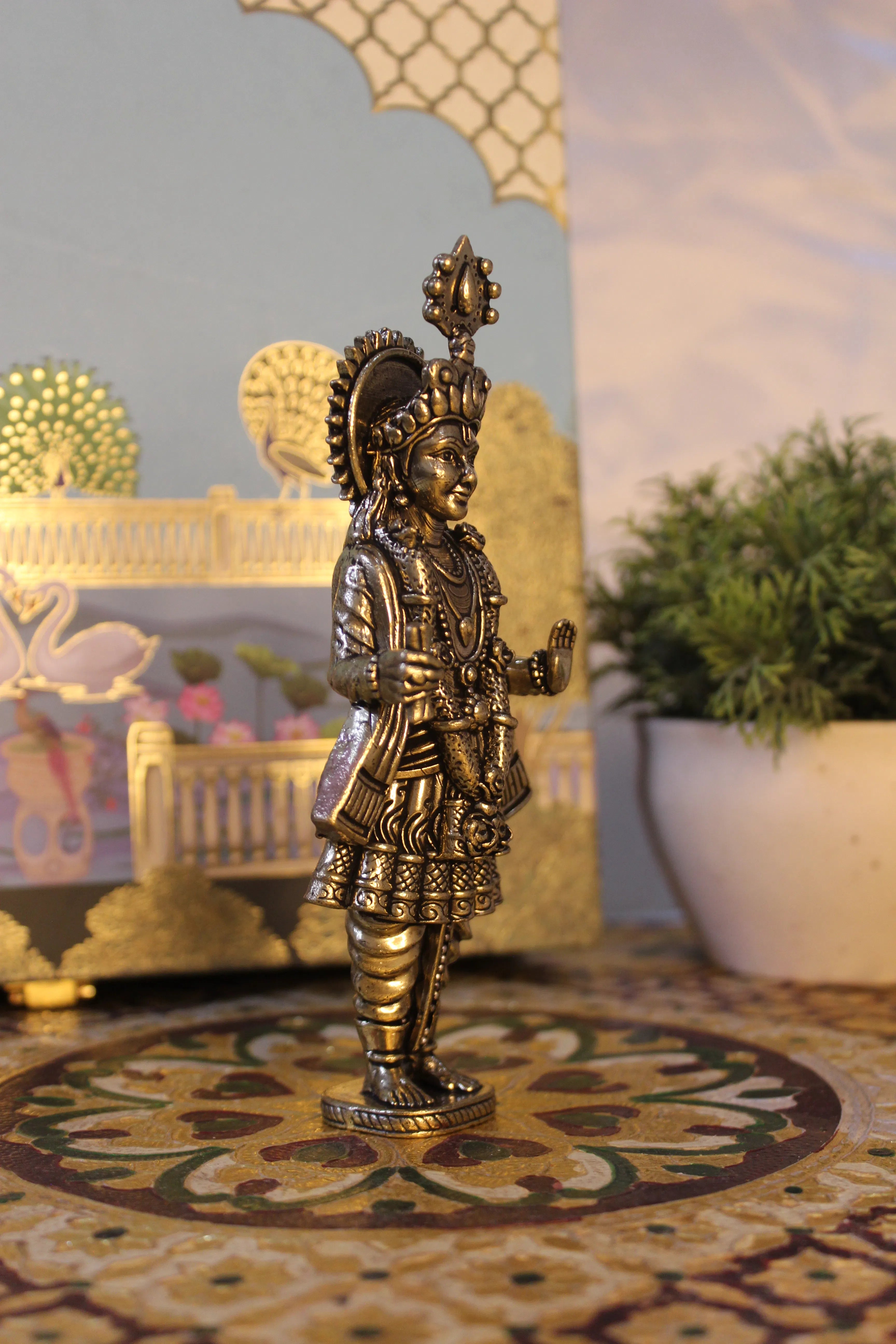 Side view of brass Narayan Swami temple idol with ornate sun disc backdrop showing profile details and mukut crown