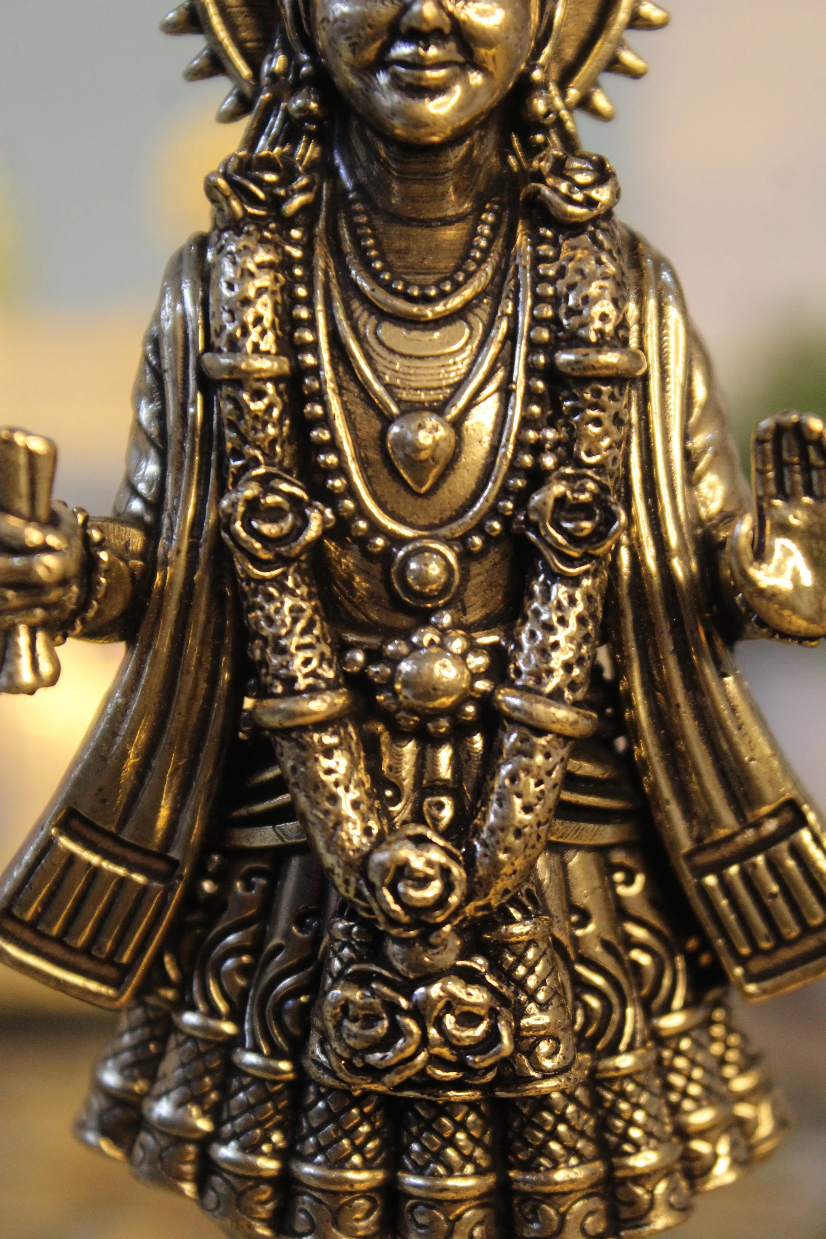 Upper body and chest detail of brass Narayan Swami idol showing intricate necklace chains and ornamental jewelry