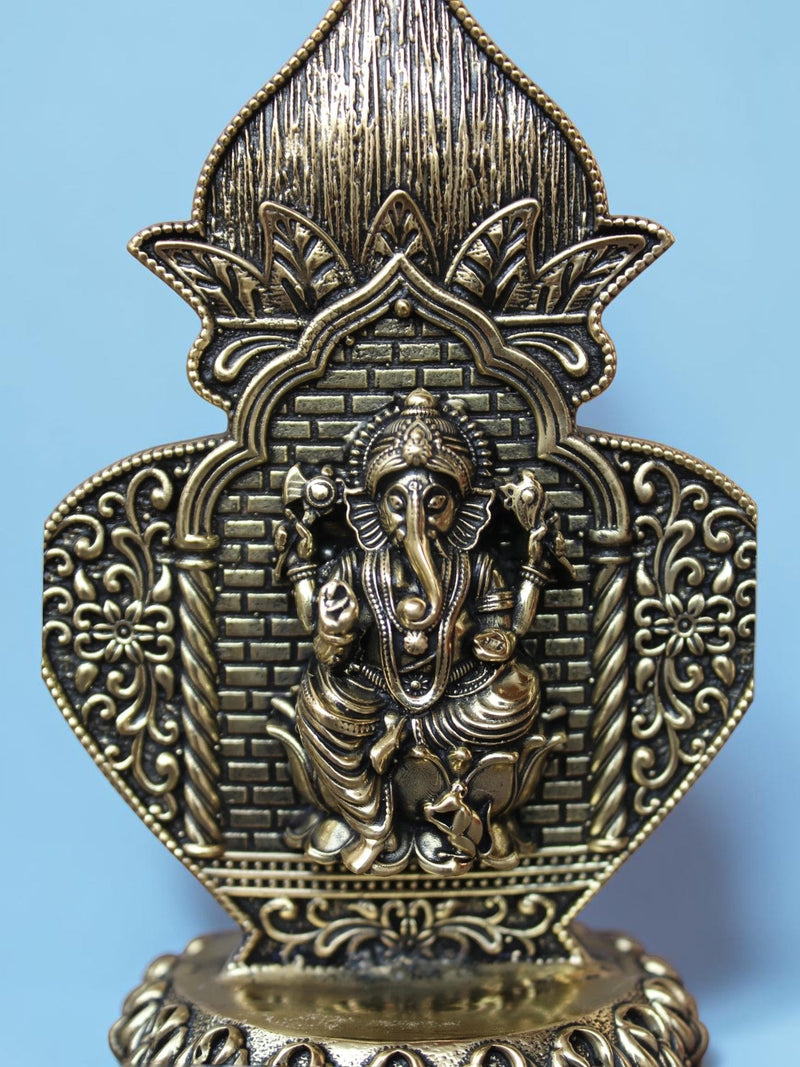 Rigvedaa™ antique gold Ganesha idol in an ornate arch frame with intricate floral motifs and lotus pedestal detail.
