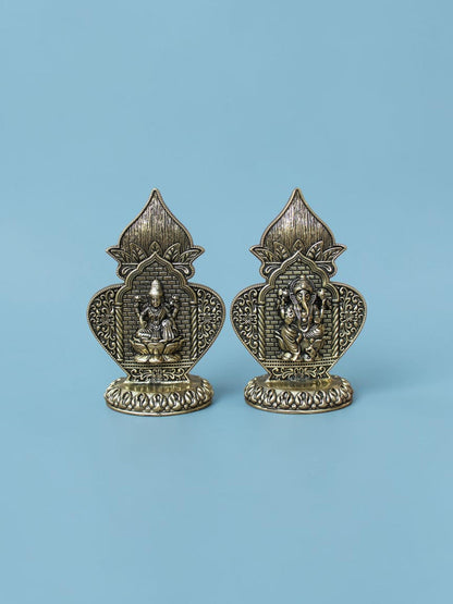 Rigvedaa™ antique gold Lakshmi and Ganesha idol set featuring ornate arch frames and lotus pedestals on blue background