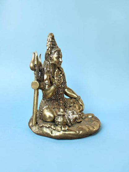 Rigvedaa™ antique gold Lord Shiva idol in a seated meditative pose with Trishul, serpent, and tiger skin base.