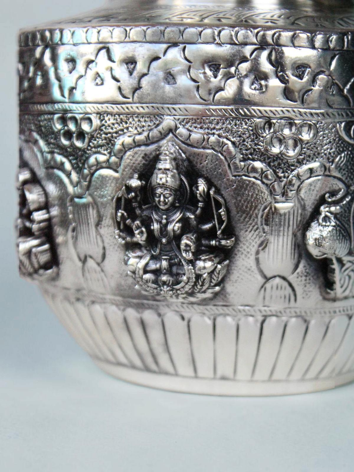 Rigvedaa™ silver plated brass Ashta Lakshmi kalash featuring intricate embossed goddess figures and floral motifs.