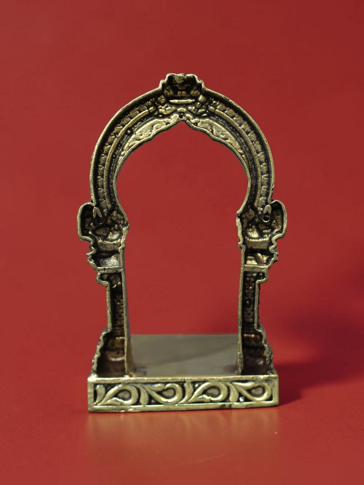 Rigvedaa™ handcrafted brass archway idol stand with intricate scrollwork and a polished golden finish.