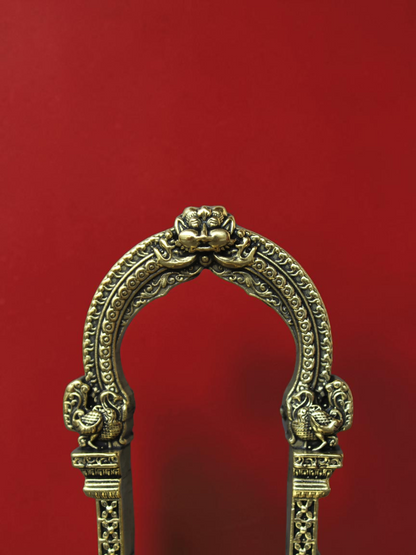 Rigvedaa™ handcrafted brass archway idol stand featuring intricate scrollwork and sculpted peacock motifs
