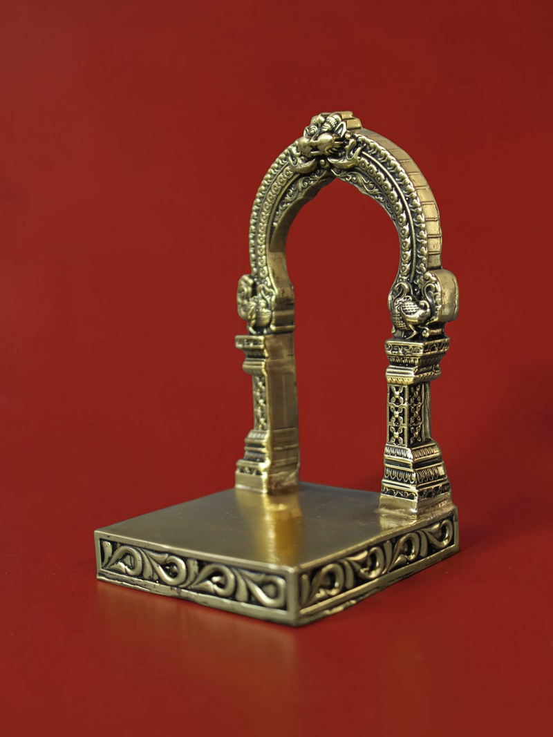 Rigvedaa™ handcrafted brass archway idol stand with intricate carvings and ornate scrollwork on a square base