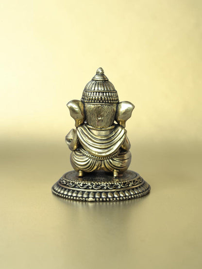 Rear view of a Rigvedaa™ brass Bal Ganesha idol showing the ornate crown and circular pedestal with antique gold finish