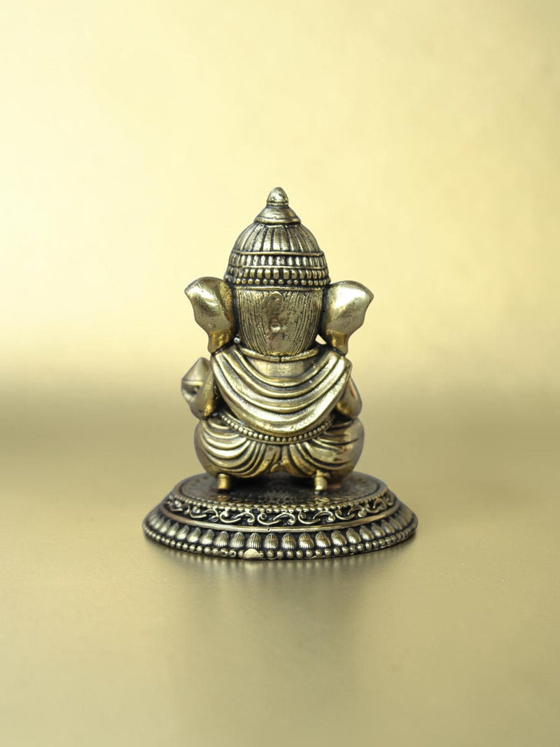 Rear view of a Rigvedaa™ brass Bal Ganesha idol showing the ornate crown and circular pedestal with antique gold finish