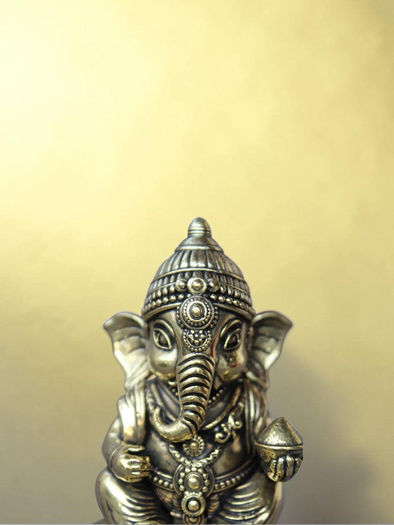 Rigvedaa™ handcrafted brass Bal Ganesha idol featuring intricate relief work and an antique gold patina finish.