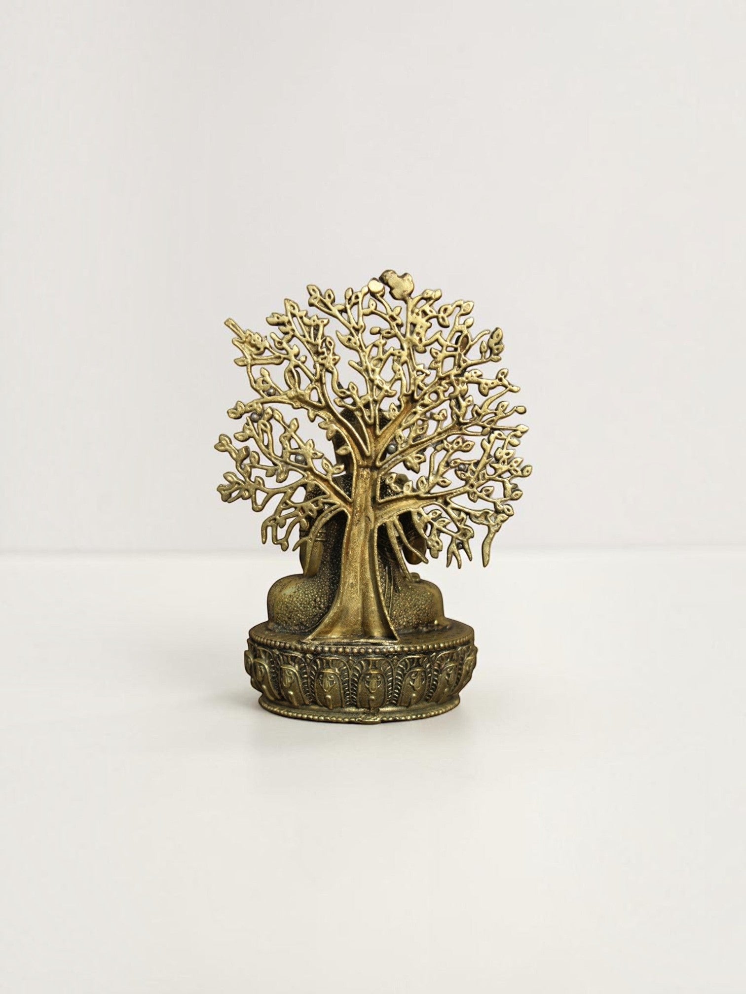 Back view of a Rigvedaa™ brass Buddha statue showing the intricate openwork Bodhi tree canopy and ornate lotus base.