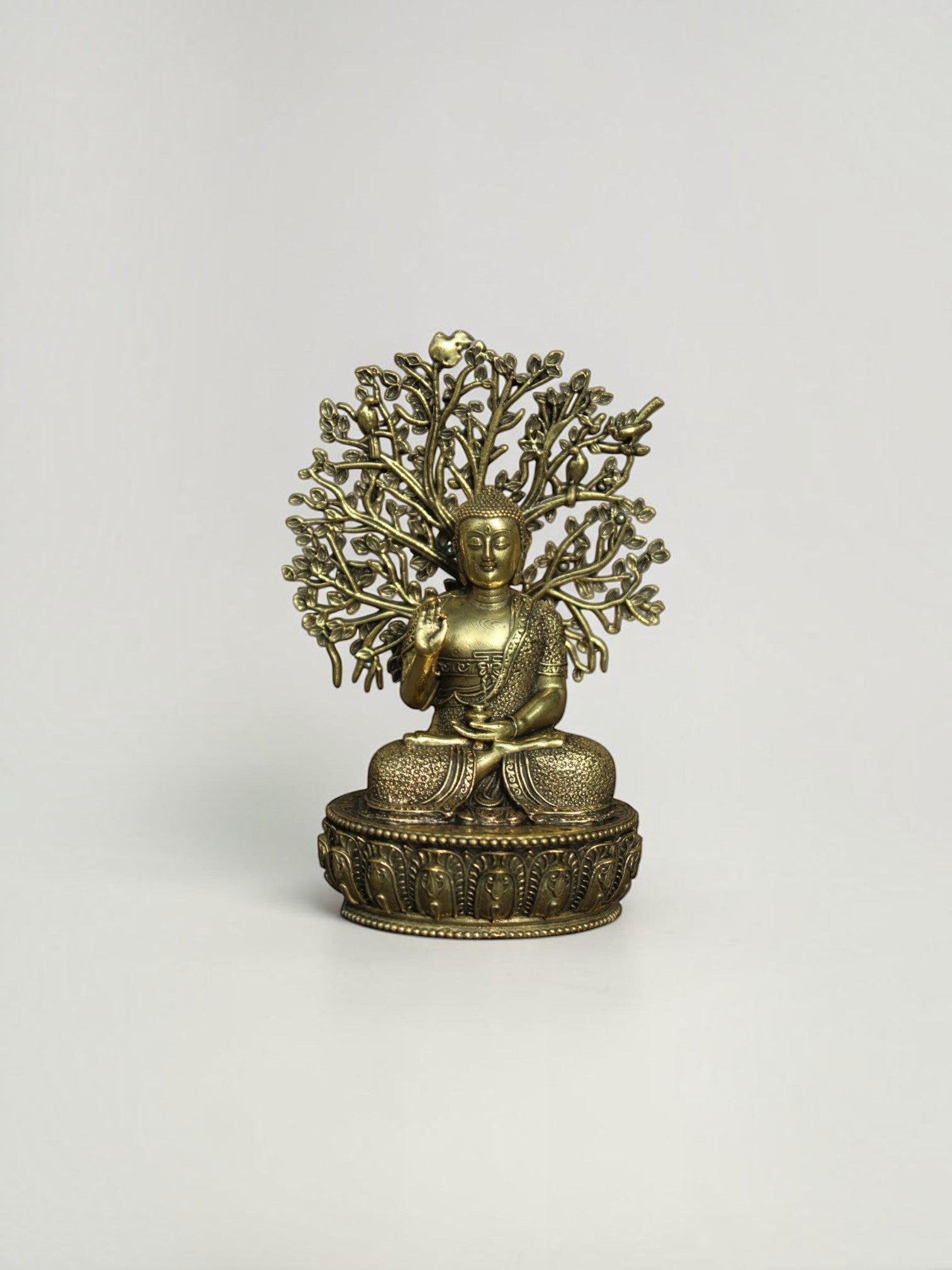 Rigvedaa™ brass Buddha statue in meditation pose under a detailed Bodhi tree canopy with an antique gold finish.