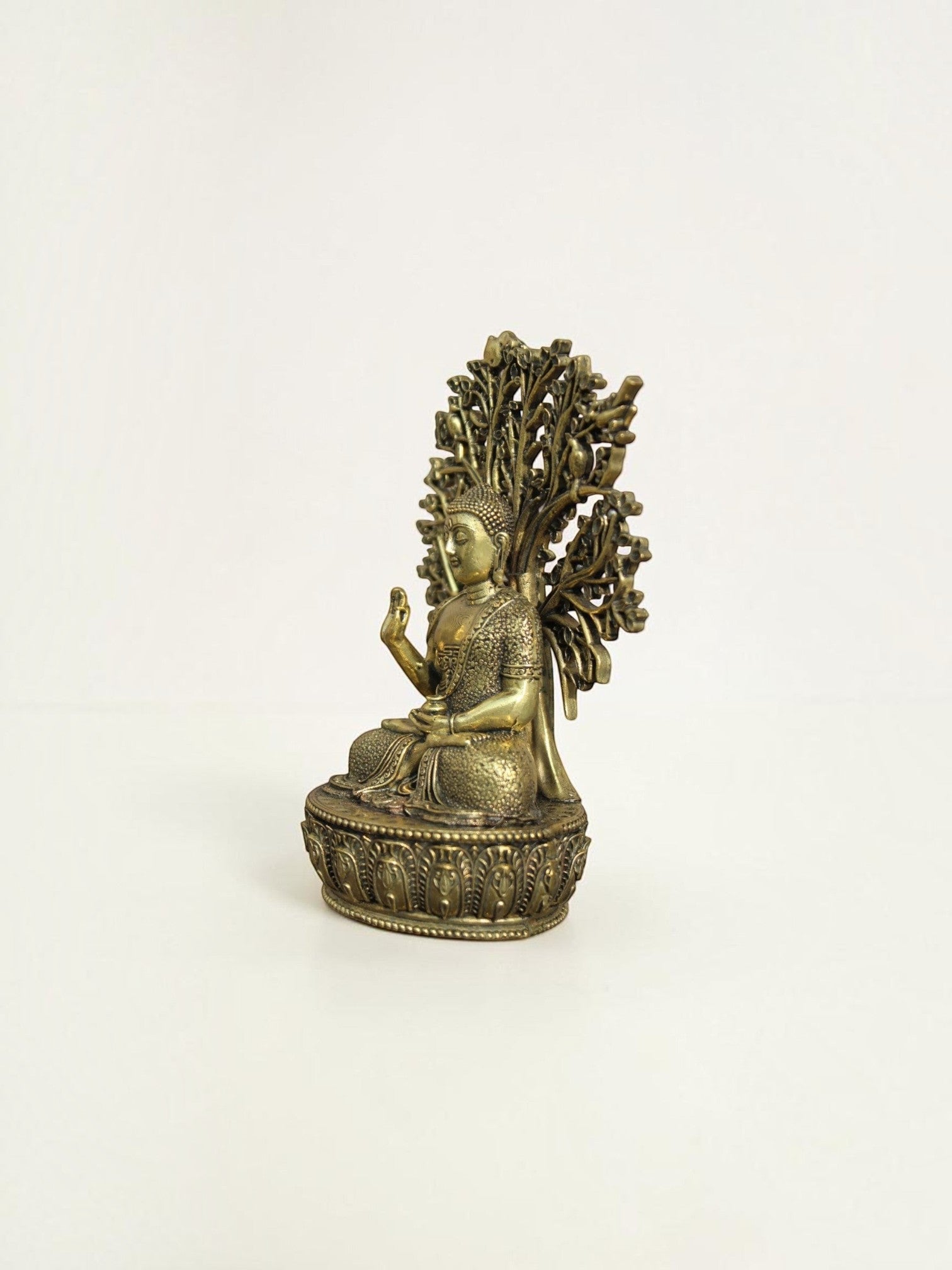 Rigvedaa™ brass Buddha statue in meditation pose under a Bodhi tree with an antique gold patina on a lotus base.