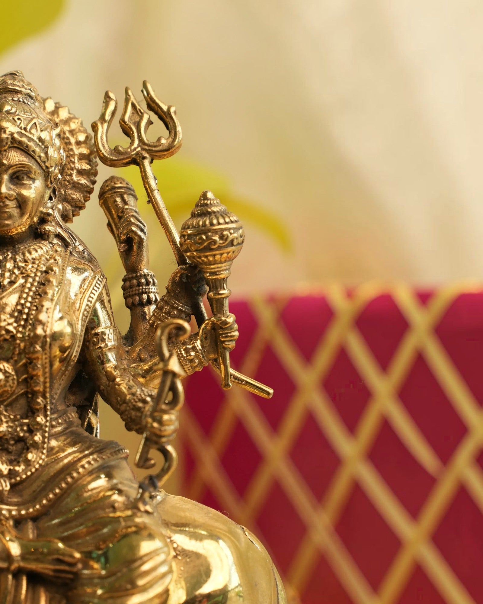 Rigvedaa™ brass Durga statue seated on lion, holding weapons and in Abhaya Mudra. Golden patina.