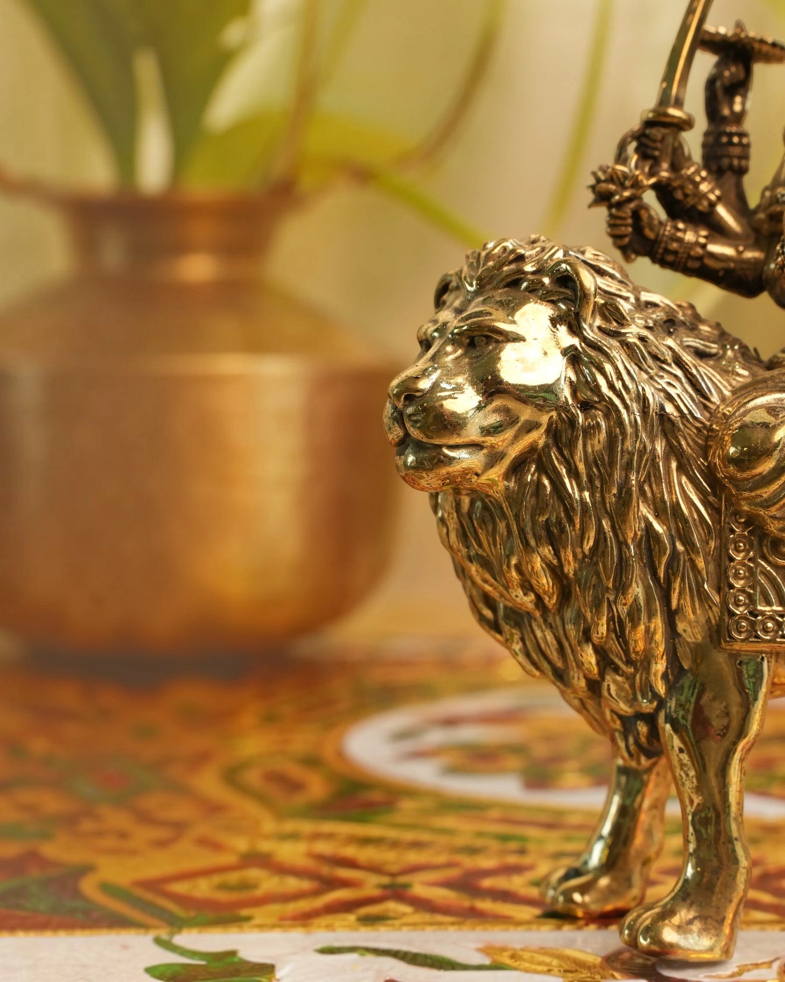 Rigvedaa brass Durga seated on lion murti, golden patina, intricate details, holding weapons, Abhaya Mudra.