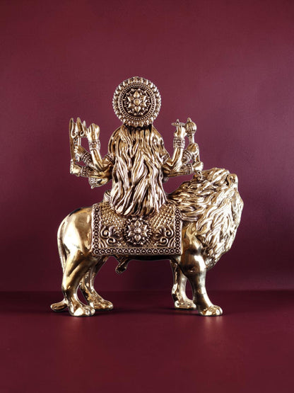 Rear view of a 12-inch Rigvedaa™ brass Goddess Durga statue seated on a lion, featuring intricate golden metalwork.