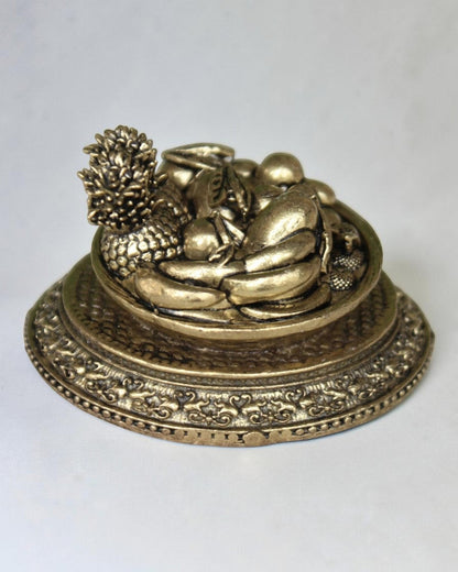 Rigvedaa™ antique gold brass miniature fruit basket idol with pineapple, grapes, and other fruits on an ornate pedestal base. Symbolizes prosperity and abundance.