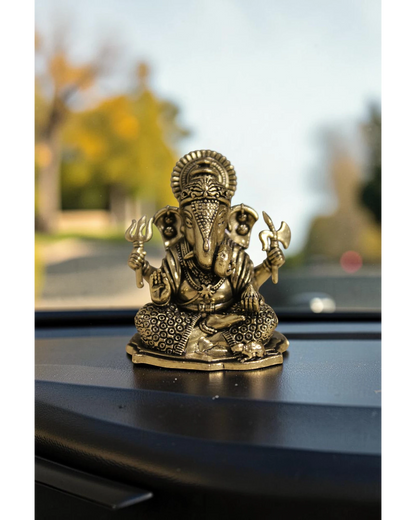 Rigvedaa™ brass Ganesha idol for car dashboard, seated with detailed ornamentation and holding symbolic items.