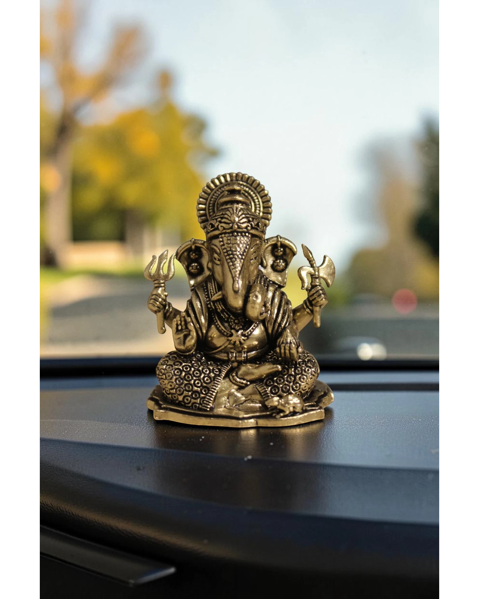 Rigvedaa™ brass Ganesha idol for car dashboard, detailed golden finish, seated pose with four arms holding symbolic items.