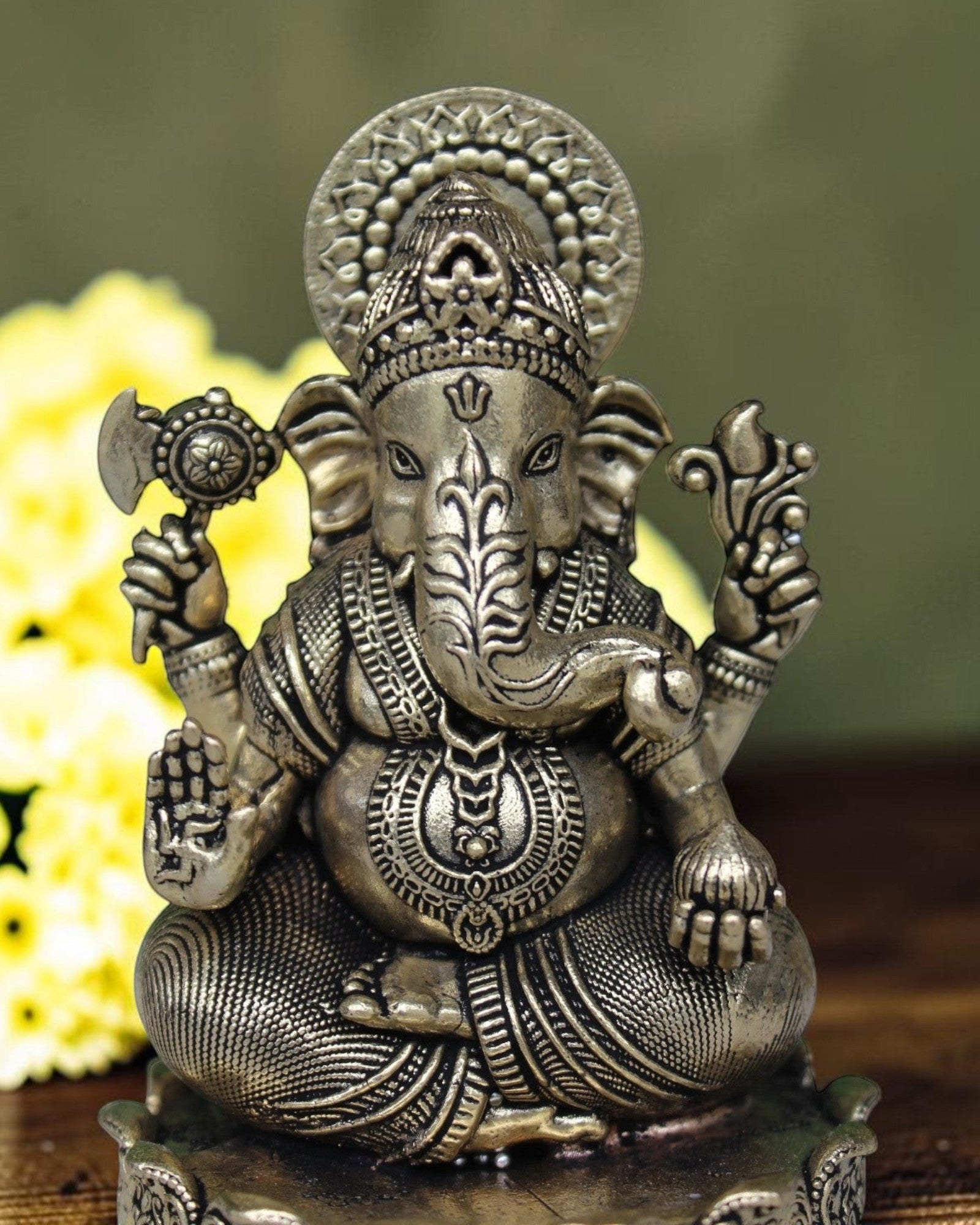 Rigvedaa™ antique brass Ganesha idol seated on a lotus base, holding an axe and a lotus flower.