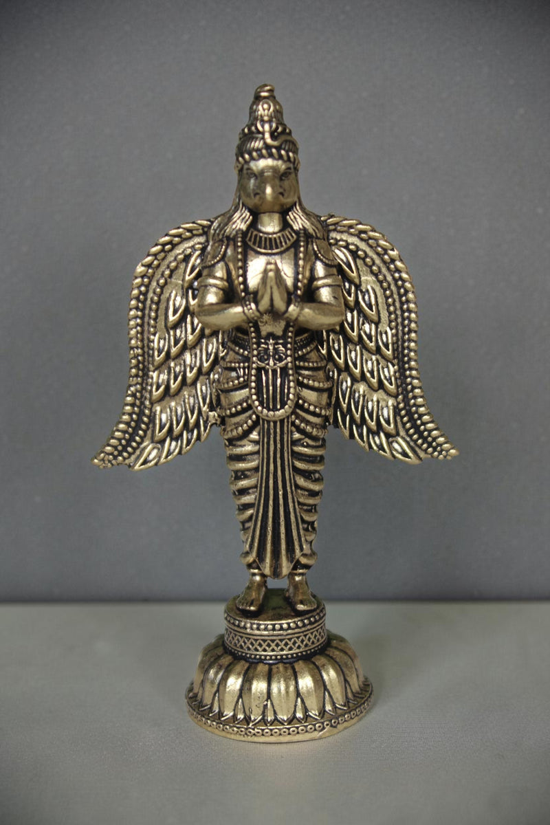 Rigvedaa brass Garuda statue with folded hands and spread wings, detailed antique gold finish, ideal for pooja decor.