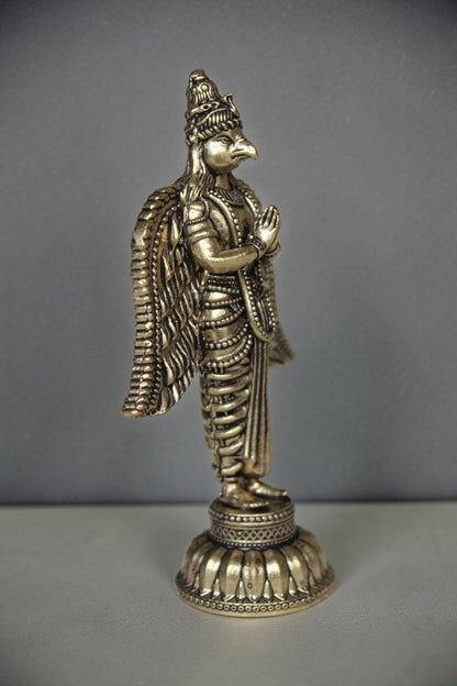 Rigvedaa brass Garuda statue with folded hands and spread wings, detailed antique gold finish, ideal for pooja decor.