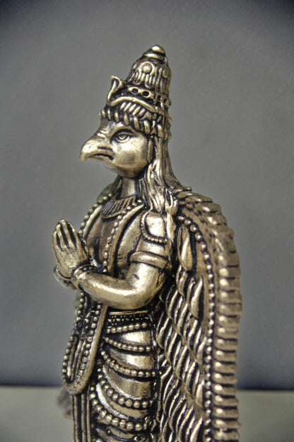 Rigvedaa brass Garuda statue with folded hands, detailed wings, and ornate headdress. Antique gold finish.