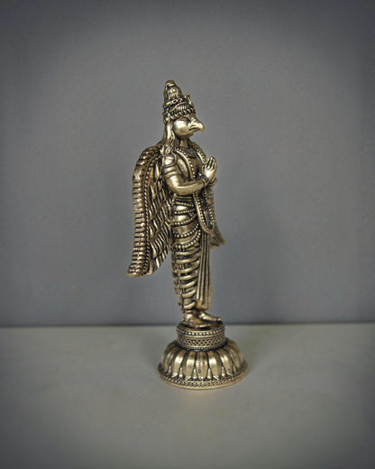 Rigvedaa brass Garuda statue with folded hands and spread wings, detailed antique gold finish, ideal for pooja decor.