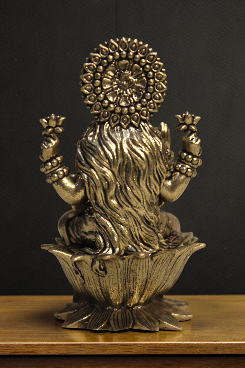 Rigvedaa brass Goddess Lakshmi idol seated on lotus, holding lotus flowers and coins. Golden finish, intricate details.