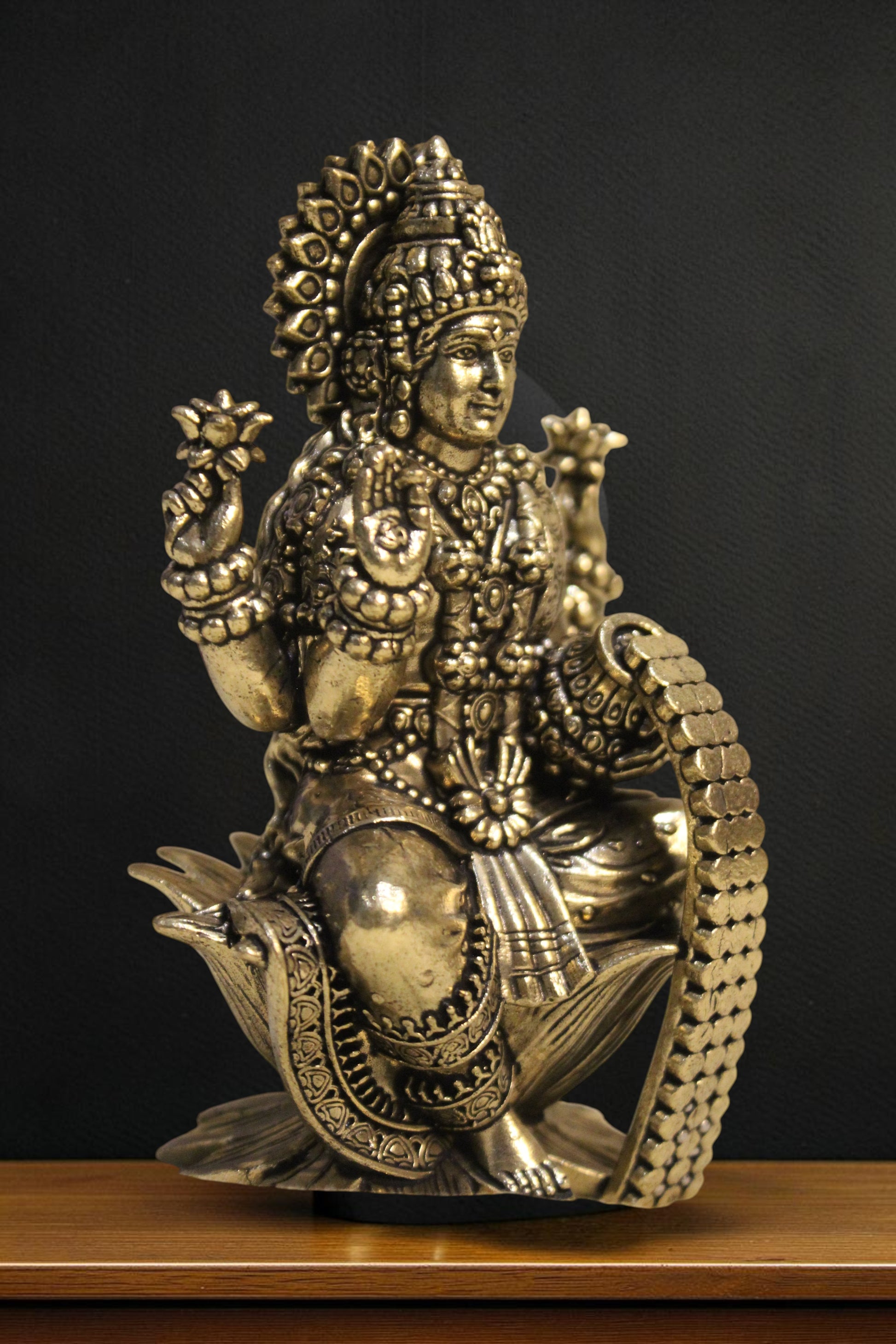 Rigvedaa brass Goddess Lakshmi idol seated on a lotus pedestal, holding lotus flowers and coins. Intricate details, golden finish.