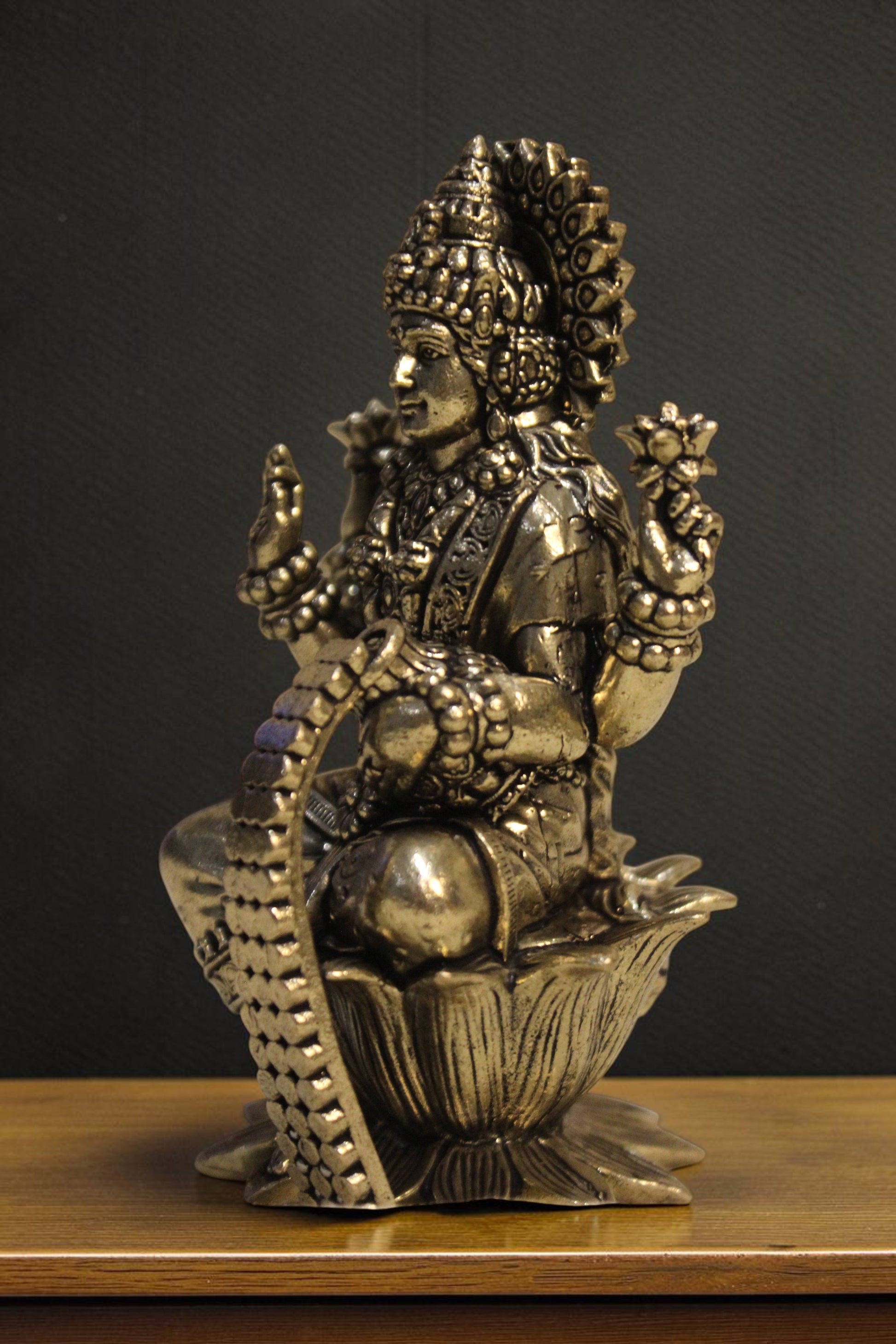 Rigvedaa brass Goddess Lakshmi idol seated on a lotus pedestal, holding lotus flowers and coins. Intricate details, golden finish.