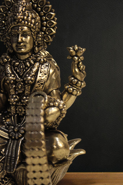 Rigvedaa brass Goddess Lakshmi idol seated on a lotus, holding lotus flowers and coins. Golden finish, 4-inch.