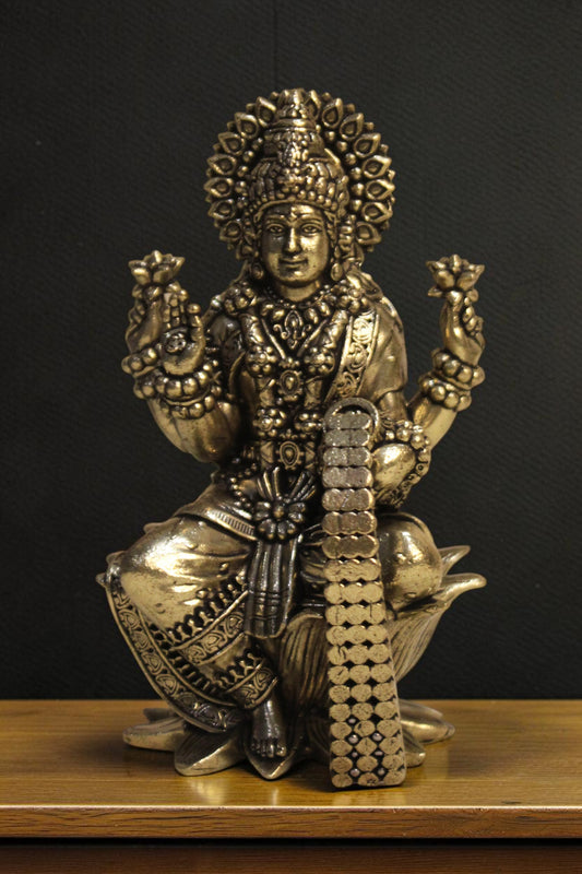 Rigvedaa brass Goddess Lakshmi idol seated on a lotus, holding flowers and coins. Golden finish, intricate details.