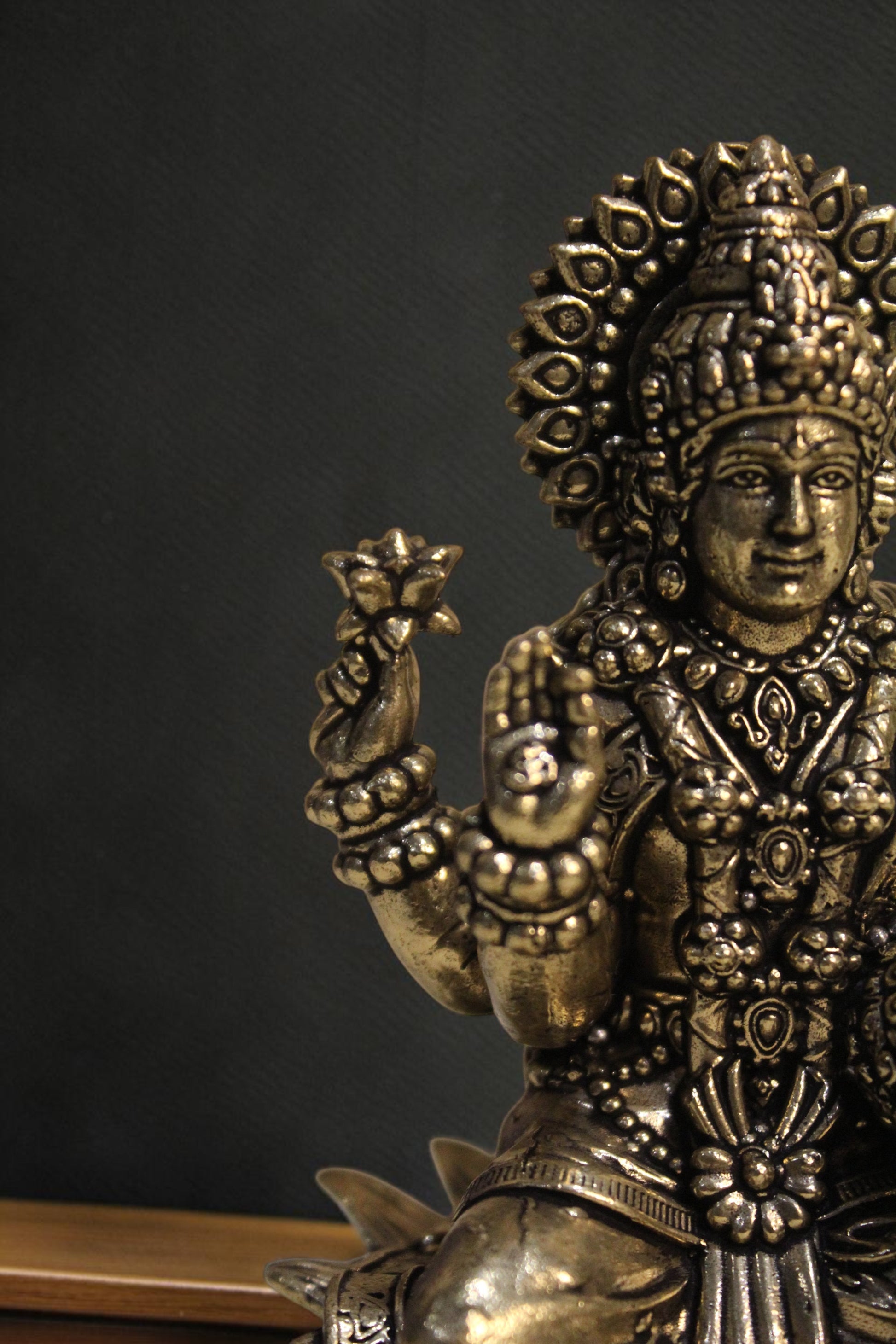 Rigvedaa brass Goddess Lakshmi idol seated on lotus, holding lotus flowers and coins. Golden finish, intricate details.