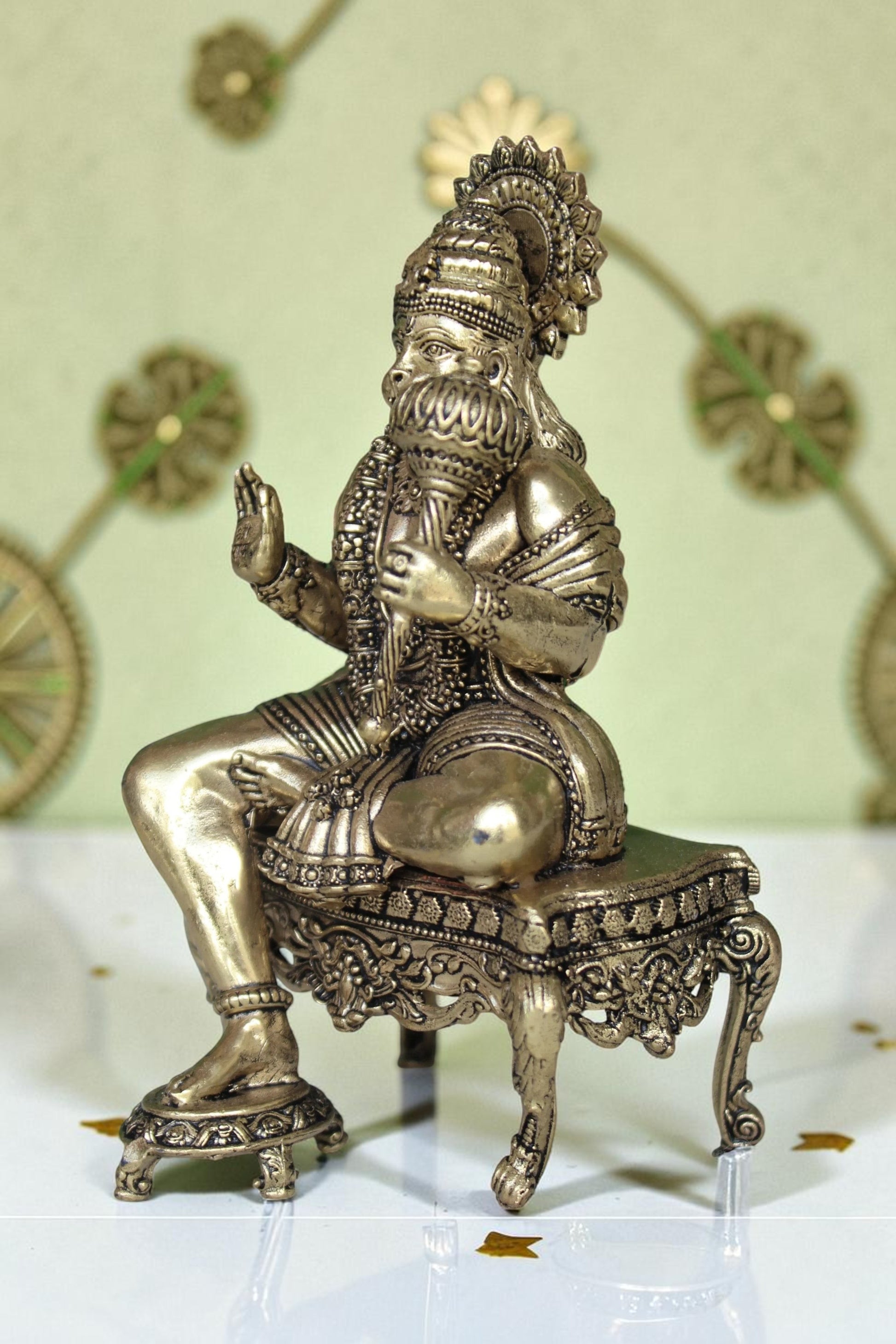 Rigvedaa™ brass idol of Lord Hanuman sitting on an ornate throne, holding a mace. Golden finish, detailed design.