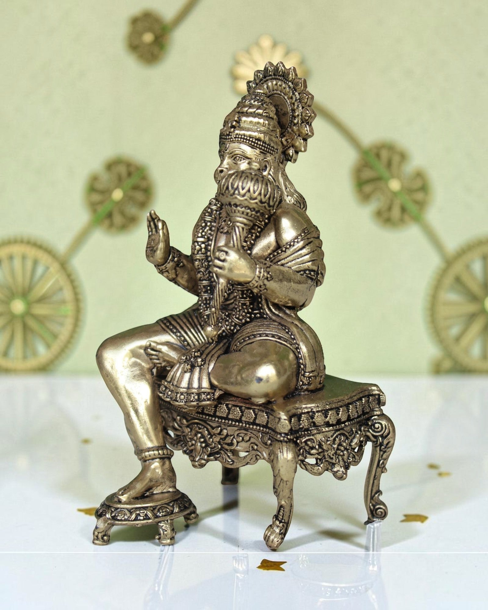 Rigvedaa™ brass idol of Lord Hanuman sitting on an ornate throne, holding a mace. Golden finish, detailed design.
