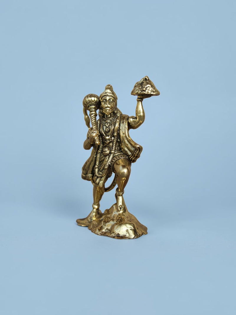 Rigvedaa™ brass Lord Hanuman idol holding a mace and mountain, featuring a polished golden finish on a blue background.