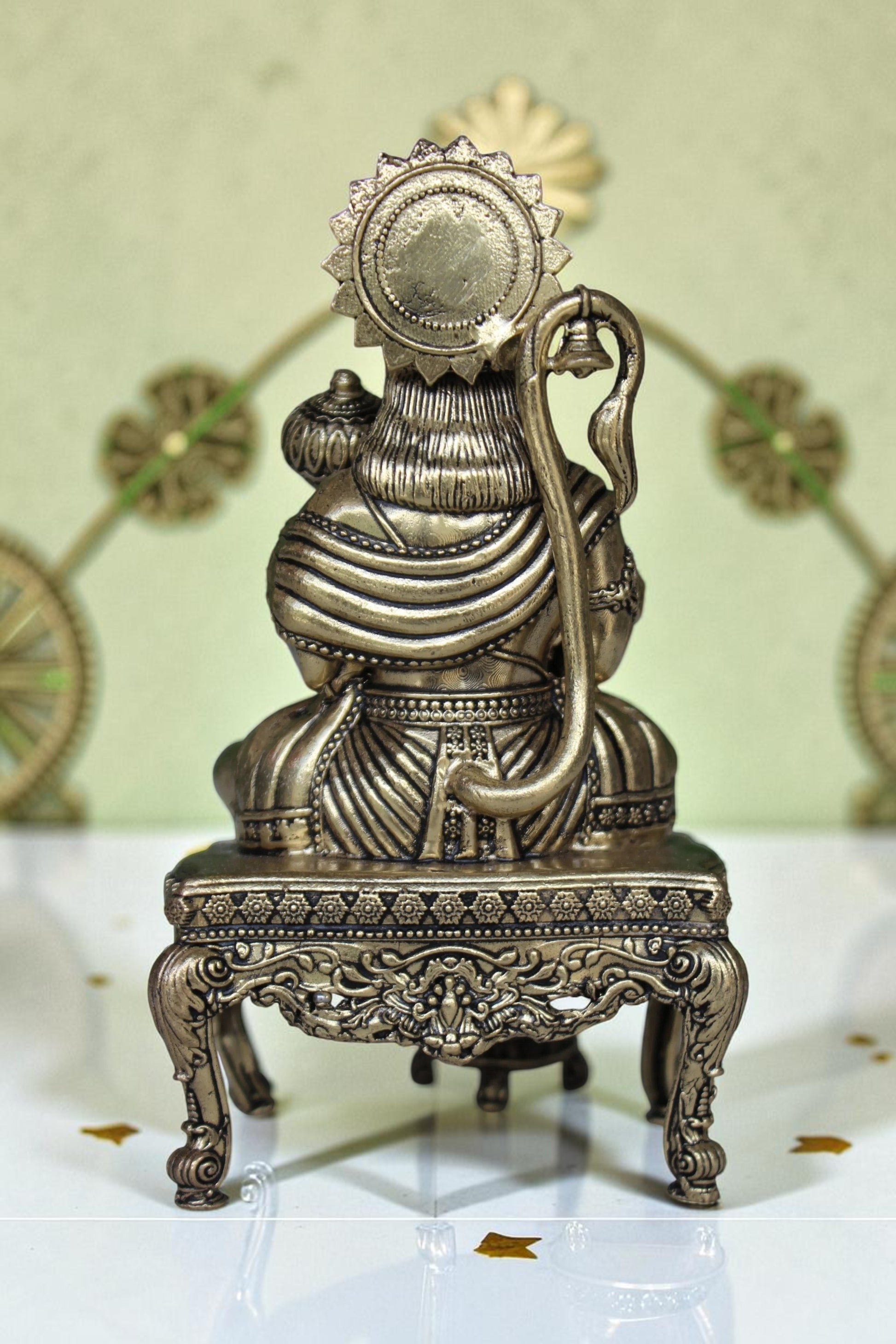 Rigvedaa™ brass Hanuman Ji idol sitting on an ornate throne, holding a mace. Golden finish, detailed craftsmanship.