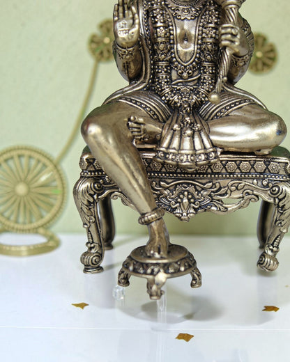 Rigvedaa™ brass Hanuman Ji idol sitting on an ornate throne, holding a mace, with intricate detailing and golden finish.