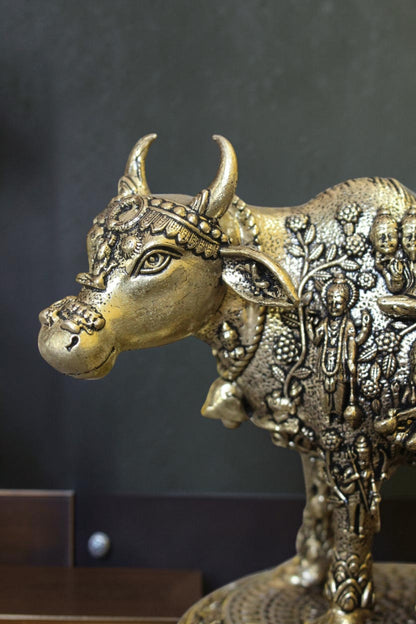Rigvedaa brass Kamdhenu cow and calf idol with engraved gods, symbolizing prosperity and divine blessings.