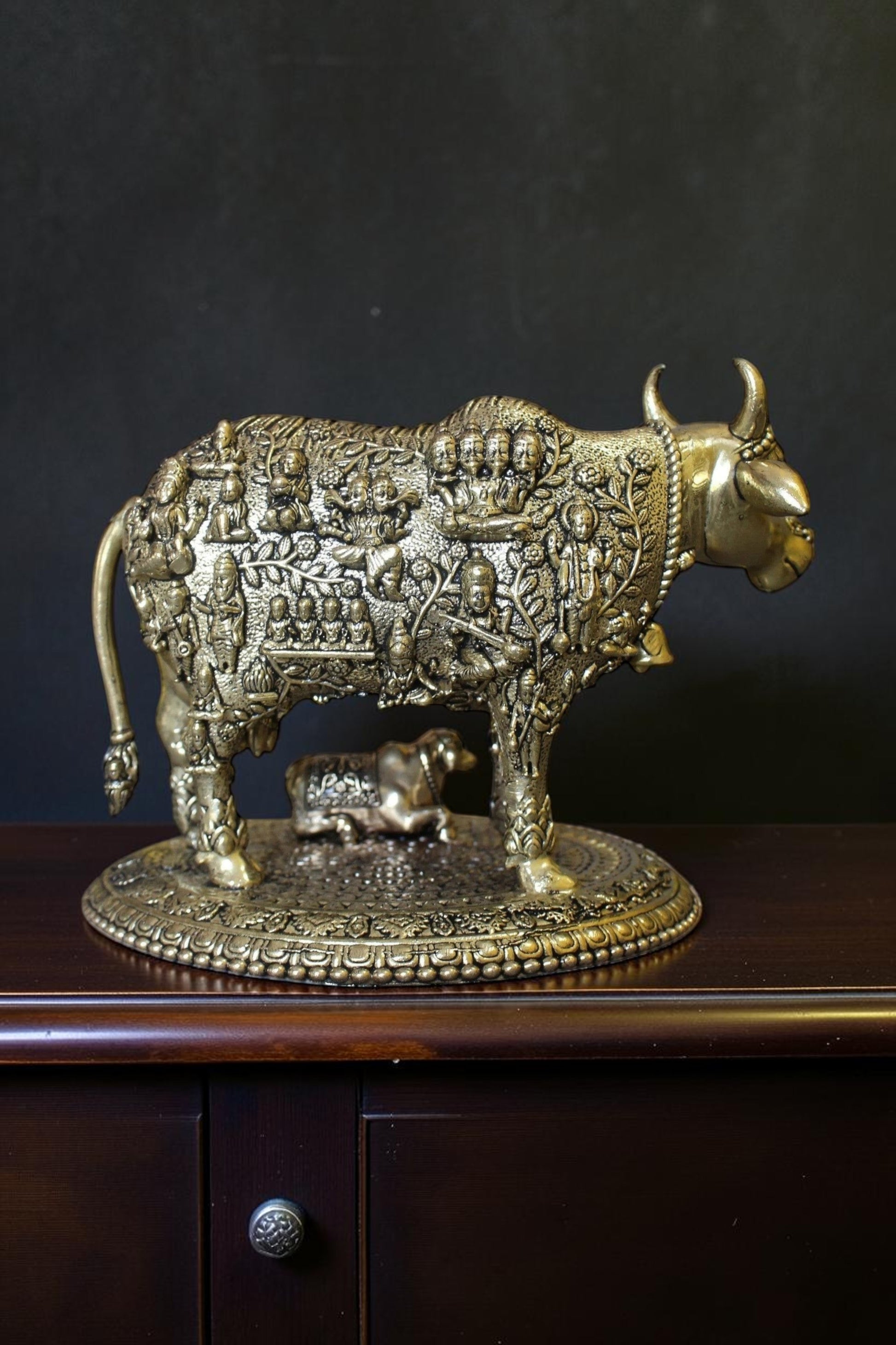 Rigvedaa brass Kamdhenu cow and calf idol with engraved gods, symbolizing prosperity and divine blessings.