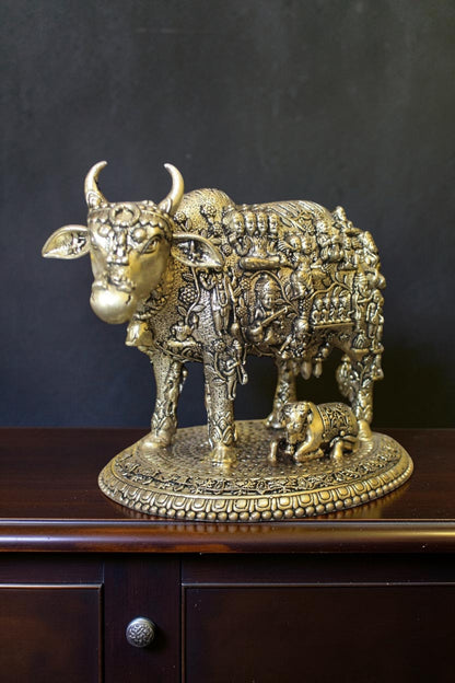 Rigvedaa™ brass Kamdhenu cow and calf idol with intricate engravings of Hindu gods, symbolizing prosperity and divine blessings.
