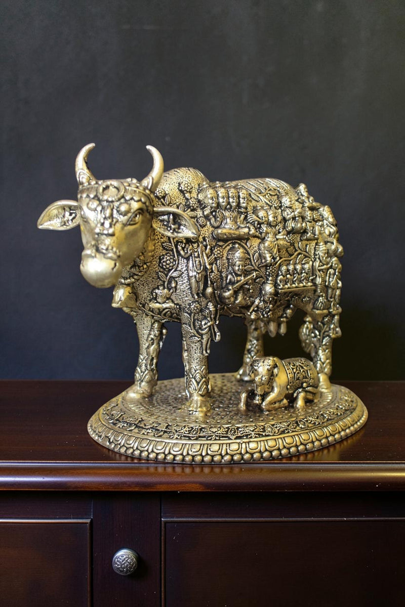 Rigvedaa™ brass Kamdhenu cow and calf idol with intricate engravings of Hindu gods, symbolizing prosperity and divine blessings.