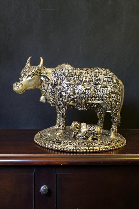 Rigvedaa™ brass Kamdhenu cow and calf idol with intricate engravings of Hindu gods, symbolizing prosperity and divine blessings.