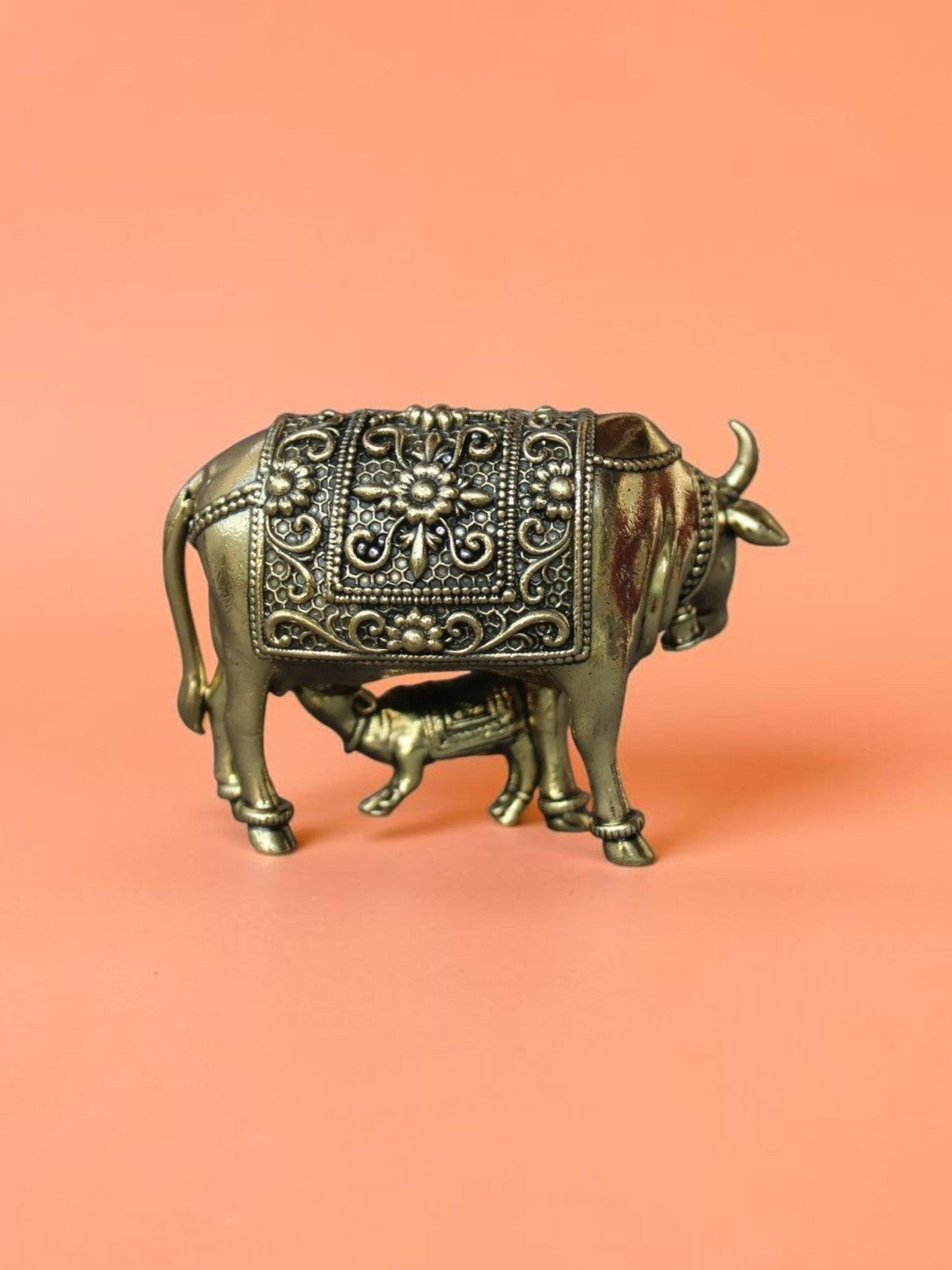 Rigvedaa™ brass Kamdhenu cow and calf idol featuring intricate floral carvings and a polished golden finish.