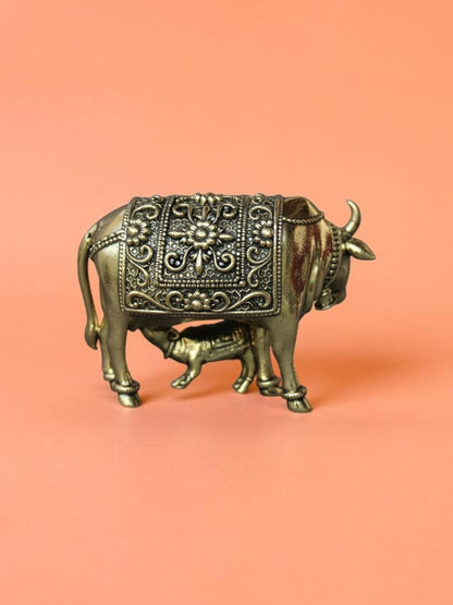 Rigvedaa™ brass Kamdhenu cow and calf idol featuring intricate floral carvings and a polished golden finish.