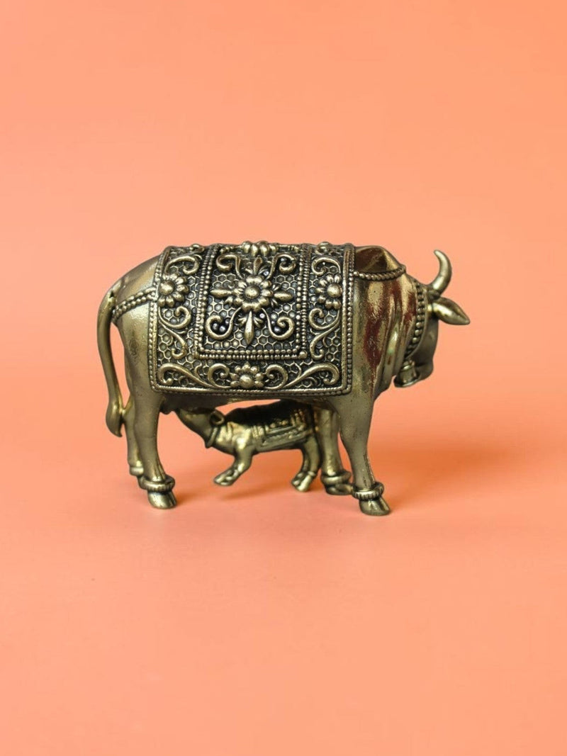 Rigvedaa™ brass Kamdhenu cow and calf idol featuring intricate floral carvings and a polished golden finish.