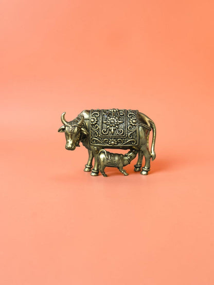 Rigvedaa™ brass Kamdhenu cow and calf idol featuring intricate floral carvings and a polished golden finish.