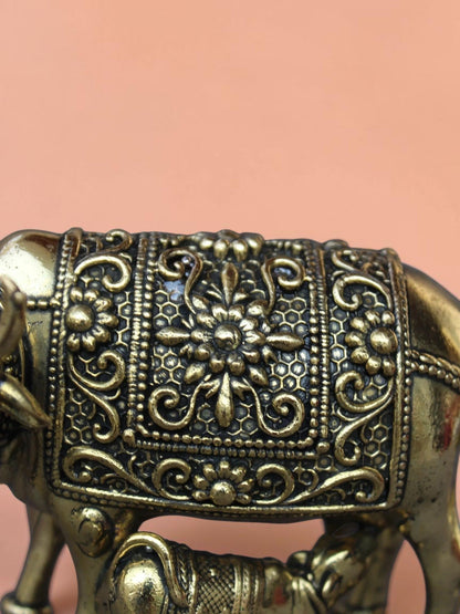 Close-up of Rigvedaa™ brass Kamdhenu cow and calf idol featuring intricate hand-etched floral relief and golden finish.