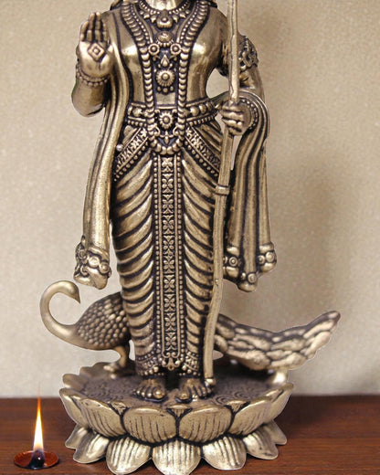 Rigvedaa brass idol of Lord Kartikeya holding a spear, standing on a lotus with peacocks. Ideal for pooja rooms.
